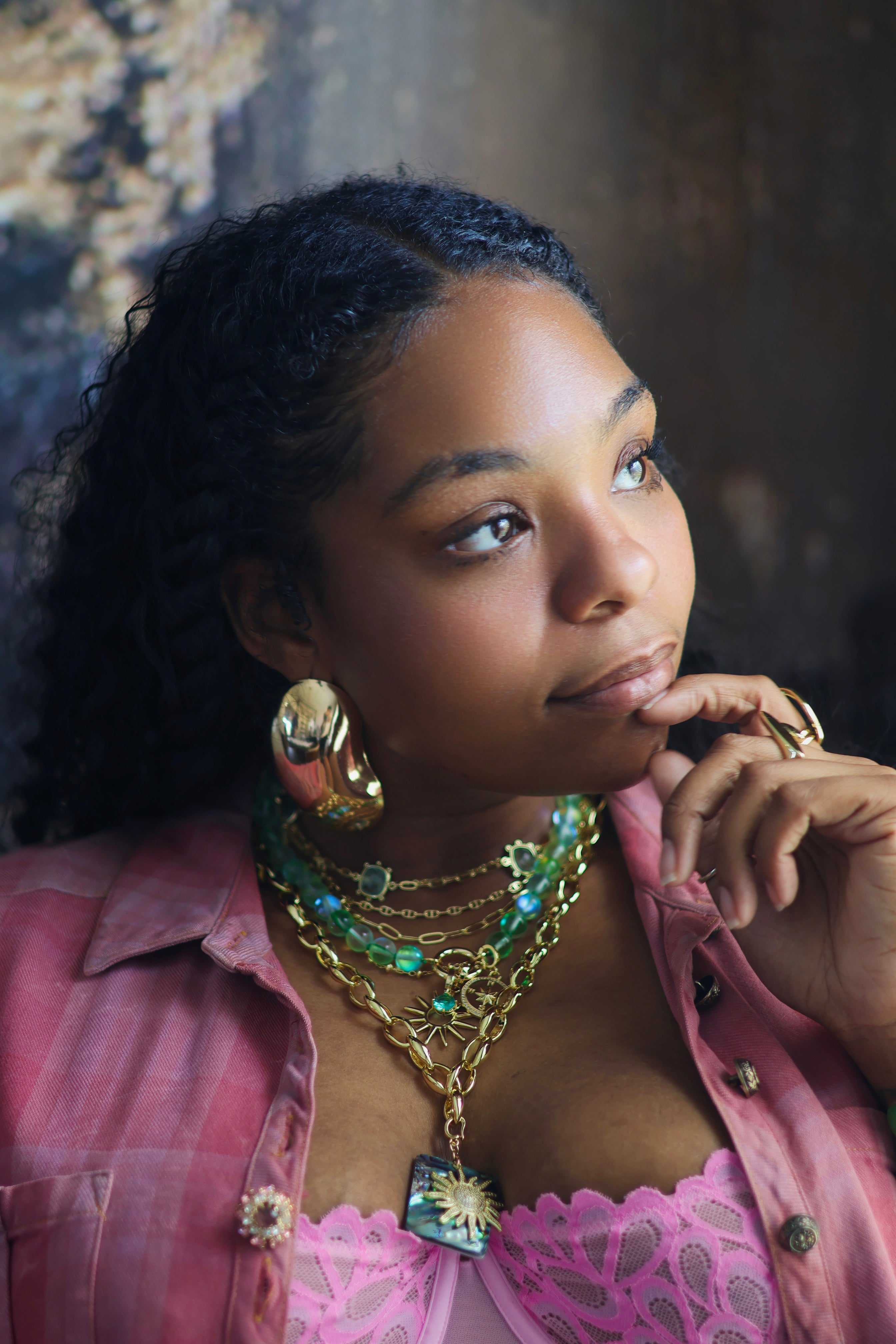 This image features a collection of vibrant and ornate jewelry, presented on a model who adds a touch of elegance. The jewelry set includes multiple necklaces with intricate designs, featuring a mix of gold and green hues, along with matching earrings and a bracelet.