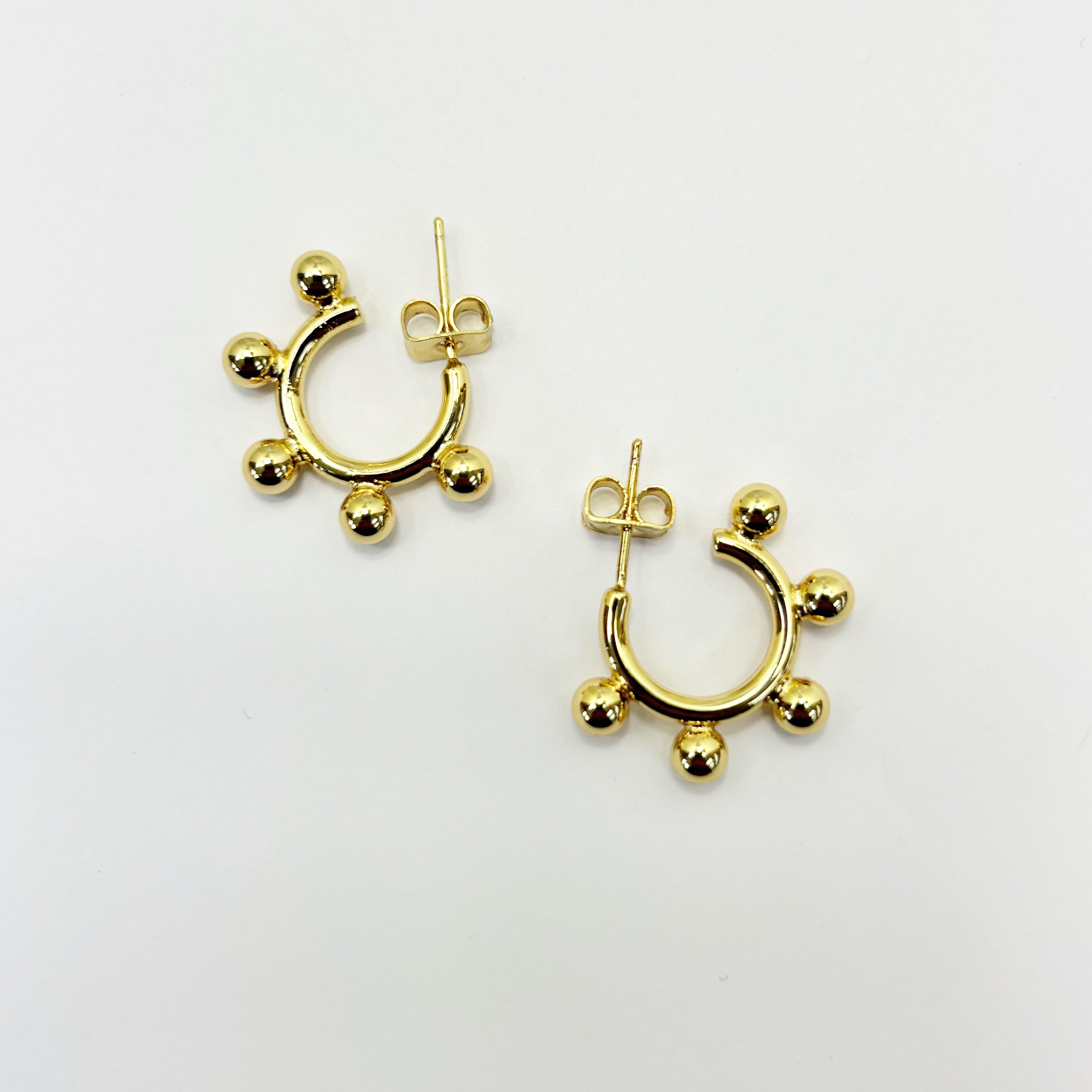 A pair of gold-colored hoop earrings with small dangling embellishments.