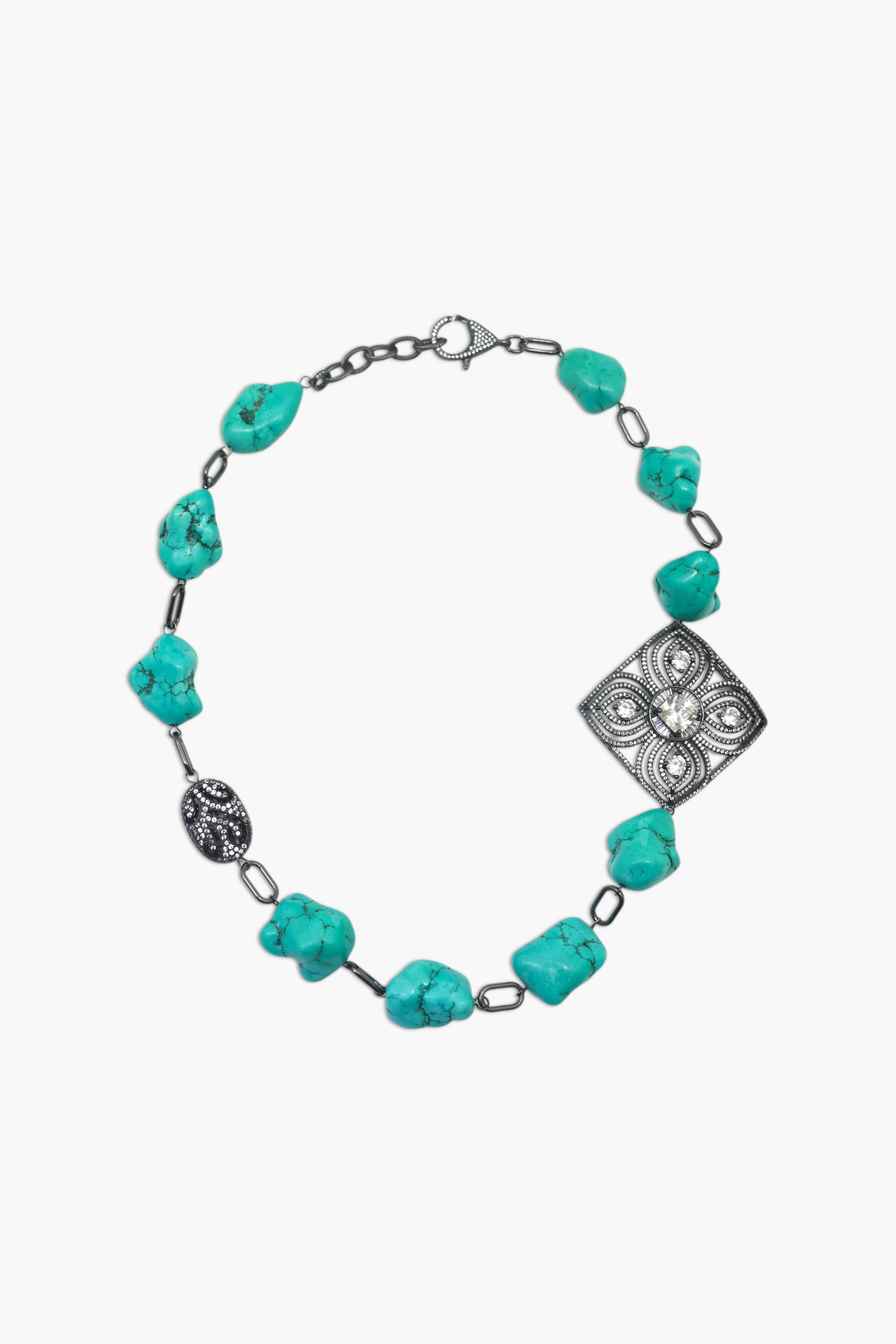 A woman wearing a turquoise and black stone necklace stack with matching earrings.