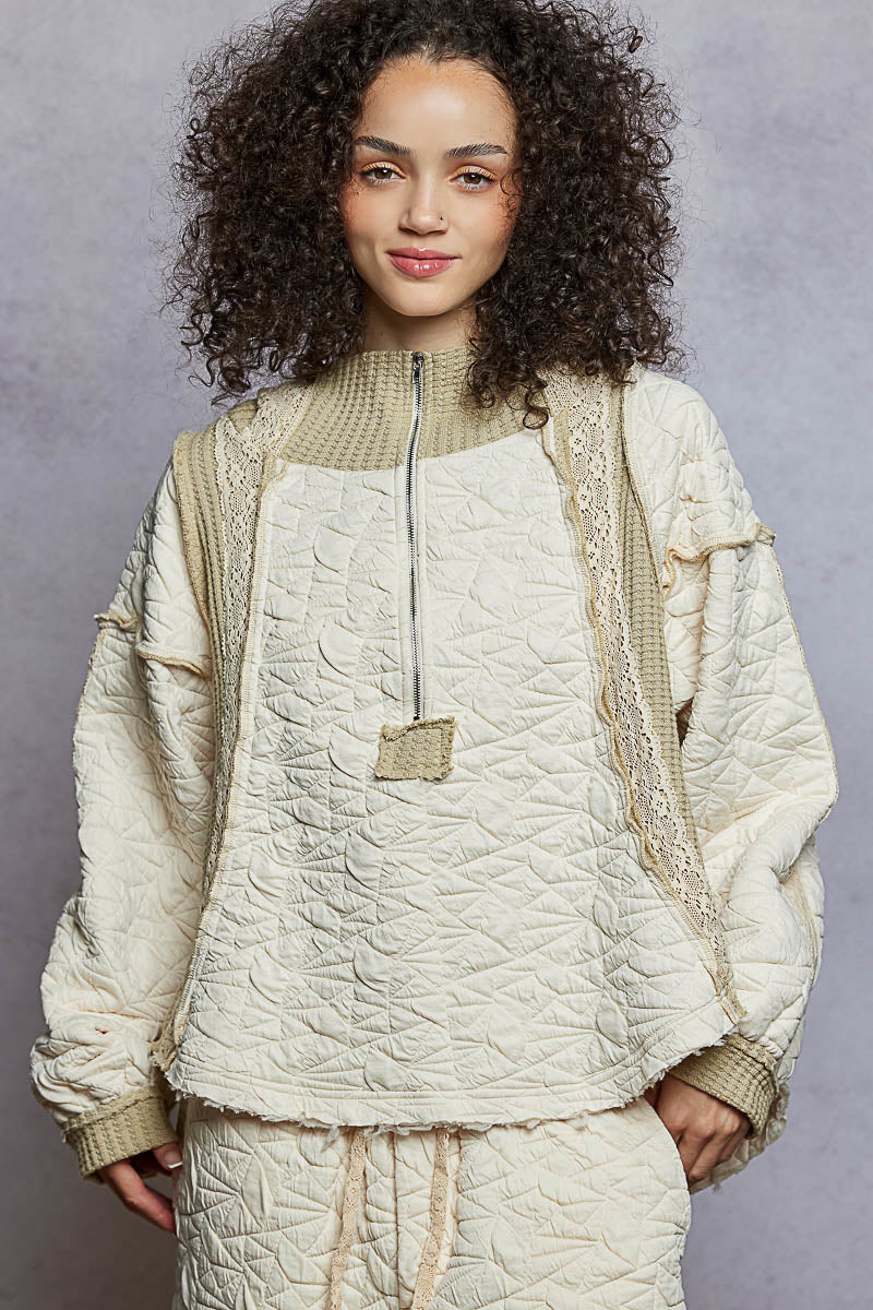 Person wearing a beige quilted jacket and pants against a gray background