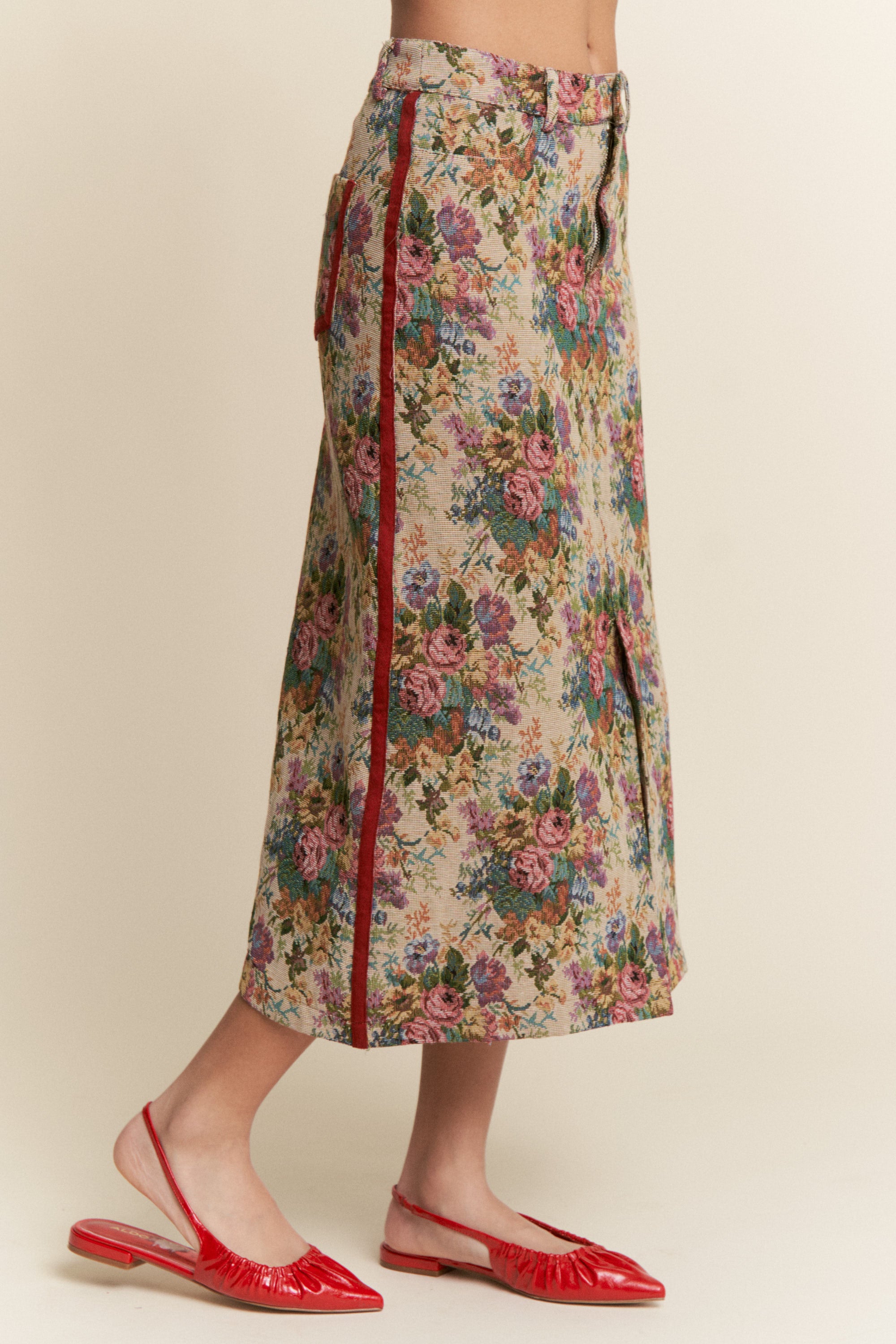 Floral skirt with red zipper and red shoes on a beige background
