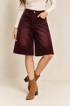 Model wearing high-waisted corduroy Bermuda shorts with wide-leg fit, front pockets, and button closure