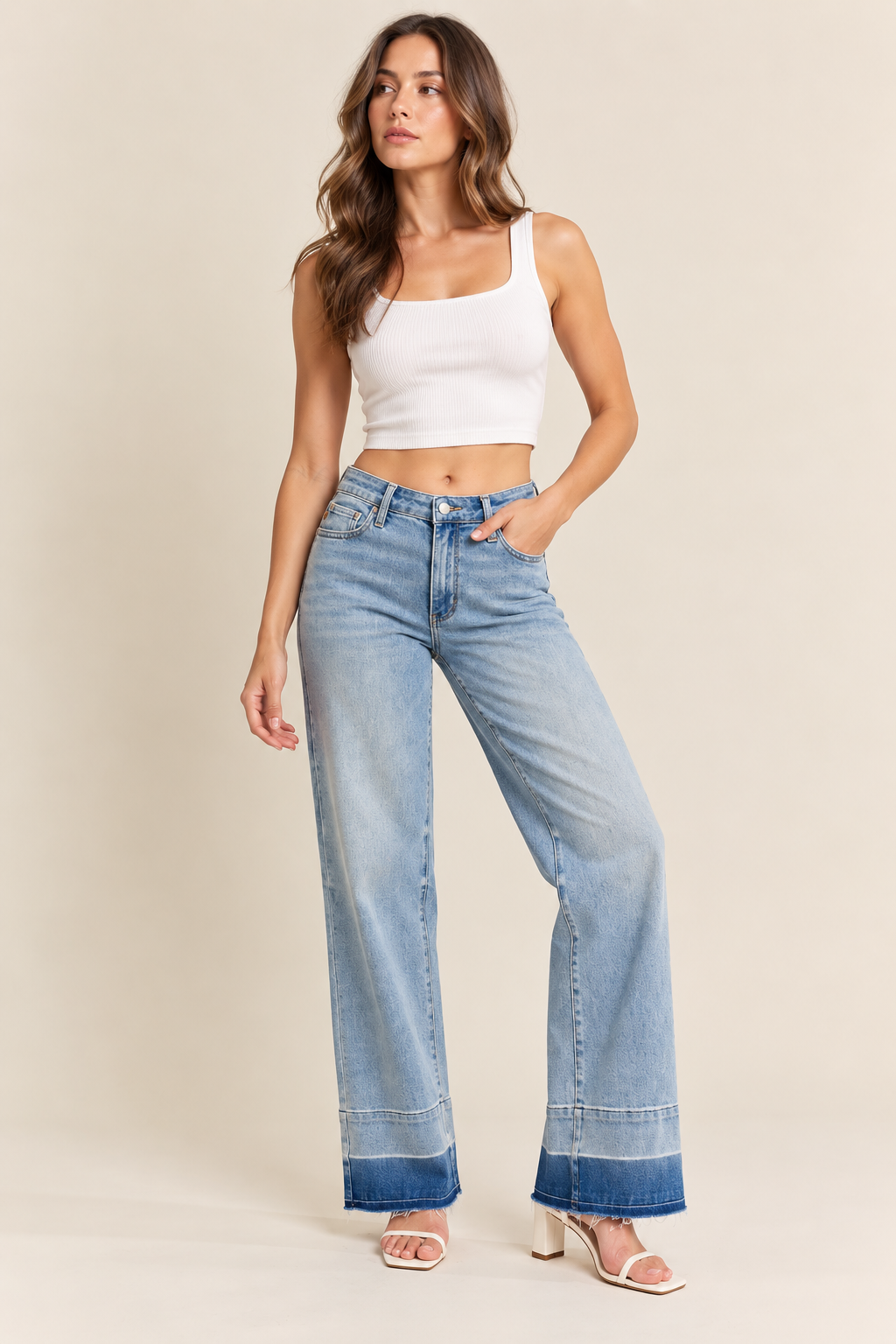 Light-wash wide-leg jeans with a high-rise waist, classic five-pocket design, subtle fading, and darker frayed cuffed hems, styled with a white ribbed crop top and white block-heel sandals.