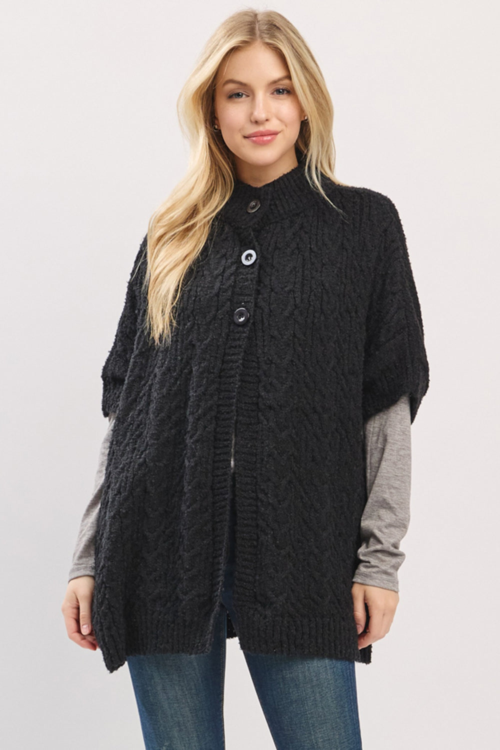 Woman wearing a black cable knit cardigan on a plain background