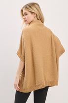 Woman wearing a beige poncho against a white background
