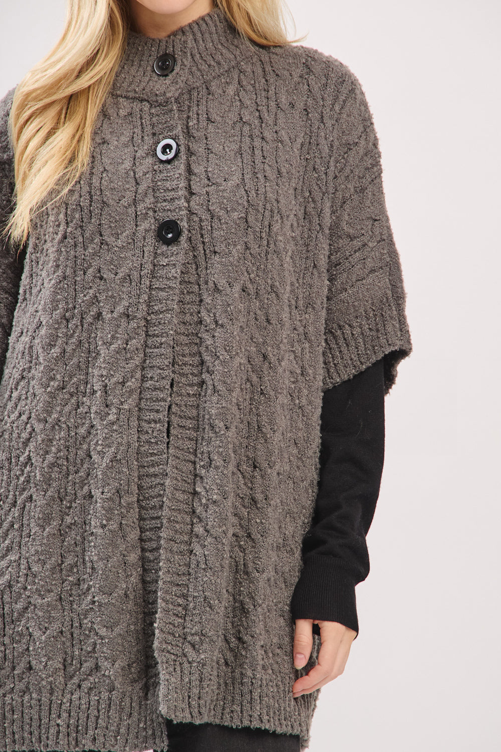 Person wearing a brown cable knit cardigan on a white background