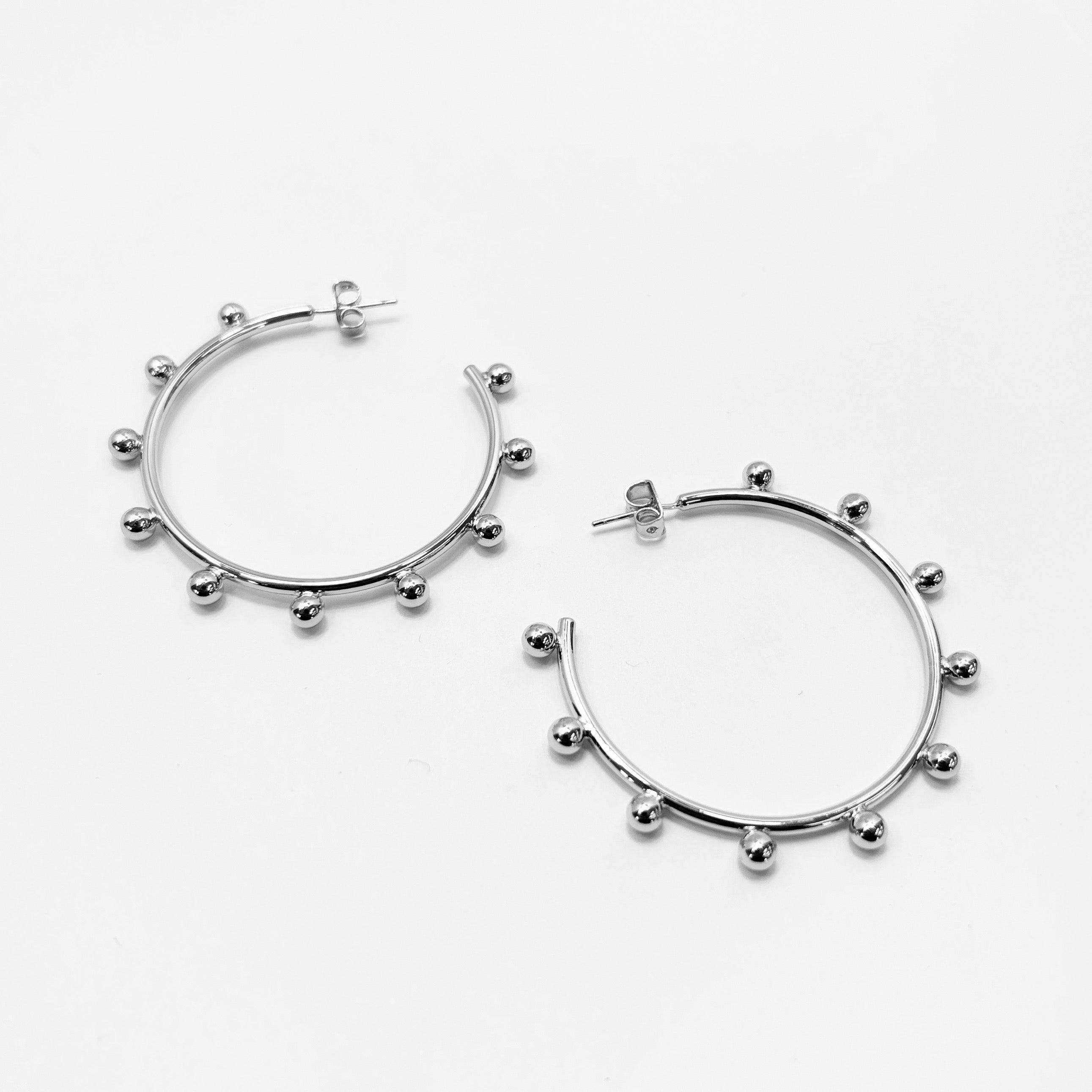 A pair of gold-colored hoop earrings with silver posts and adornments.