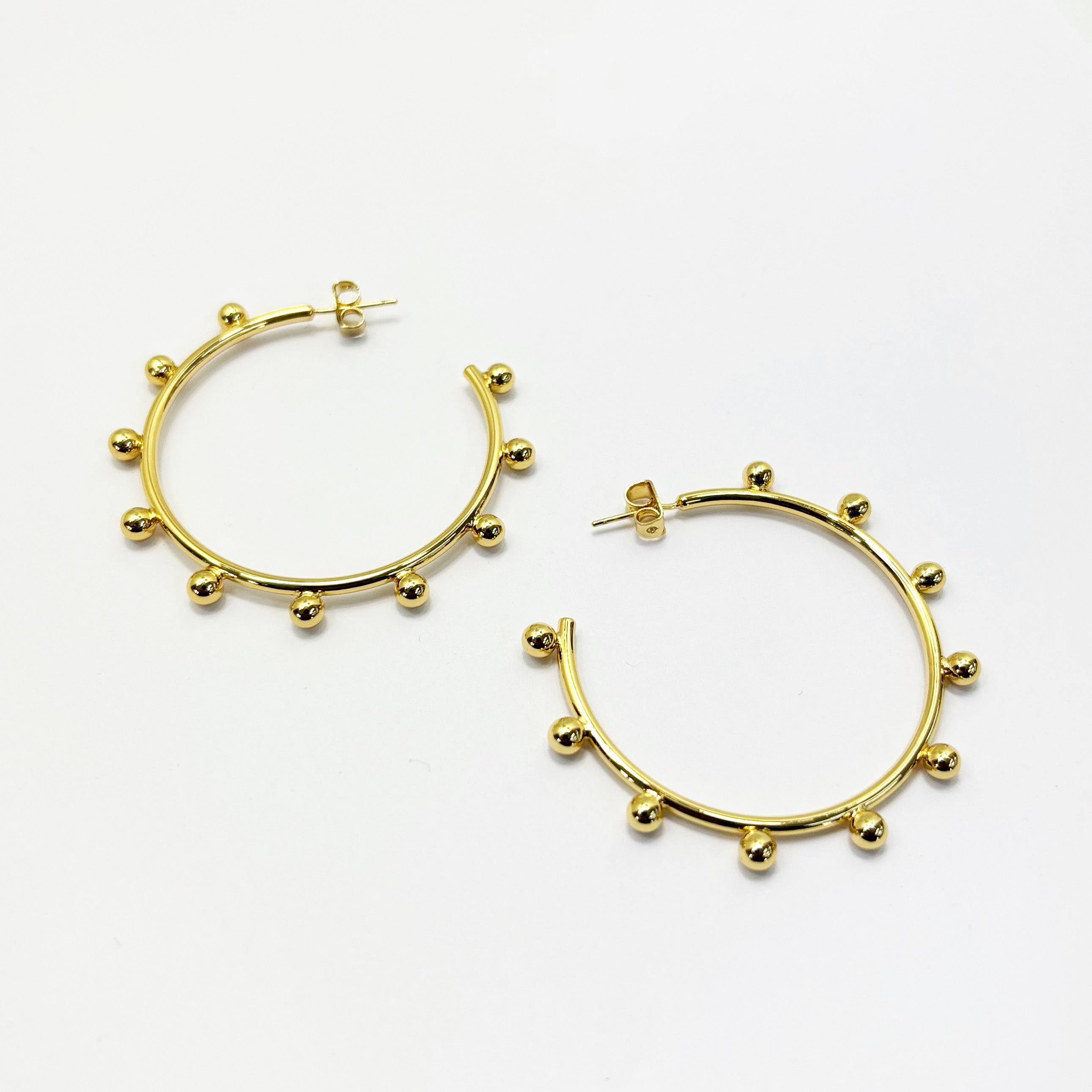 A pair of gold-colored hoop earrings with silver posts and adornments.